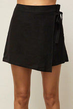 Load image into Gallery viewer, The model is wearing Crescent Adella Wrap Skort. The Item looks as a skirt in front and has shorts at the back. The skirt is black, features wrap detail.   (7756356157648)
