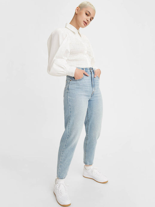 Woman is wearing Levi's high loose taper fit jeans. Jeans feature a flattering high rise, stacked, tapered leg and fitted with a relaxed silhouette. Jeans are paired with a white blouse. (7721824452816)