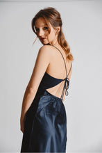 Load image into Gallery viewer, Woman is wearing Molly Bracken strappy cowl neck slip dress. Dress features cowl neck, adjustable straps and crisscross tie back. the dress is navy blue. The photo demonstrates the back of the dress. (7724325011664)
