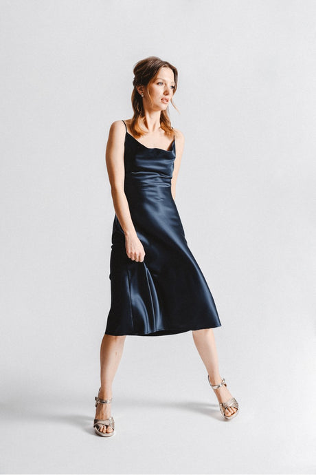 Woman is wearing Molly Bracken strappy cowl neck slip dress. Dress features cowl neck, adjustable straps and crisscross tie back. the dress is navy blue.. (7724325011664)