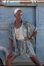 Load image into Gallery viewer, The model is wearing Molly Bracken High waisted shorts and shirts with leaf-like blue prints with white knitted tanktop and beige high heel boots (7724308365520)

