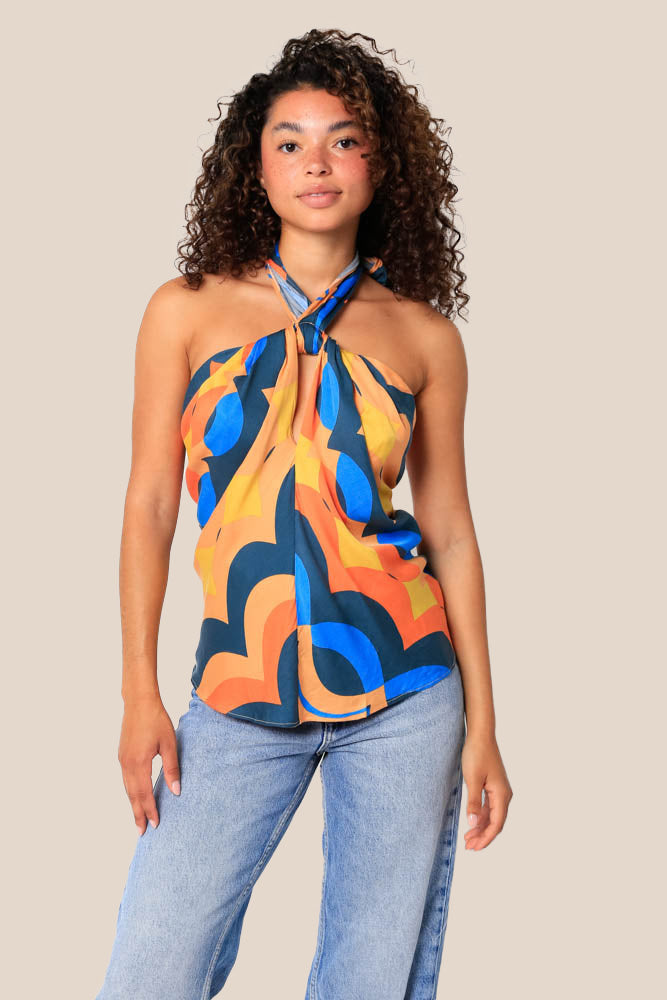 The woman is wearing Olivaceous Hali top. The top features halter neck and draped bodice. The Olivaceous top is multicolor print, it has chaotic blue, orange and yellow lines.   (7756326830288)