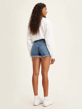 Load image into Gallery viewer, woman is wearing Levi&#39;s 501 original high rise shorts. These denim shorts feature high waist, vintage-inspired fit and chewed hem. Denim shorts are paired with a white Levi&#39;s sweatshirt and white sneakers. The photo demonstrates the outfit from the back. (7721829892304)
