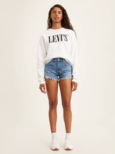 Load image into Gallery viewer, woman is wearing Levi&#39;s 501 original high rise shorts. These denim shorts feature high waist, vintage-inspired fit and chewed hem. Denim shorts are paired with a white Levi&#39;s sweatshirt and white sneakers. (7721829892304)
