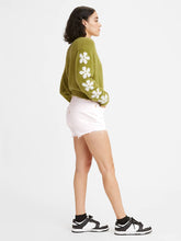 Charger l&#39;image dans la galerie, Women is wearing Levi&#39;s 501 Original High Waist shorts. Jean shorts are white color and feature high waist, loose fit and chewed hem. Jean shorts are paired with green sweater. The photo demon trates the model from the side. (7721826975952)
