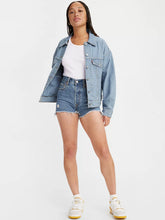 Load image into Gallery viewer, Woman is wearing Levi&#39;s ribcage shorts. Denim shorts feature flattering high waist, slightly loose fit and chewed hem. Denim shorts are paired with a white top, light denim striped jacket and white sneakers. (7721844310224)
