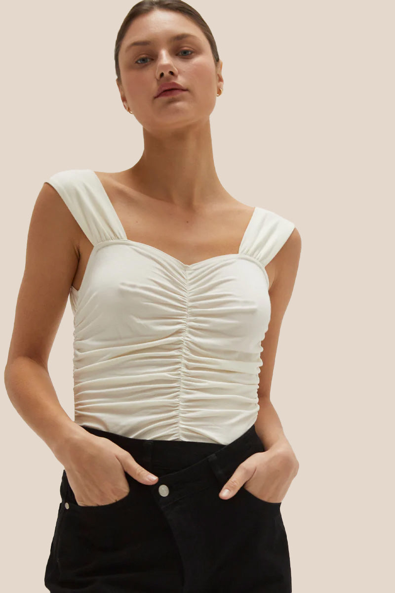 the model is wearing crescent arosa gathered sleeveless top. the top is ivory color, features all-over gathering detail with thick shoulder straps in a fit-to-bodice silhouette.  (7756403507408)